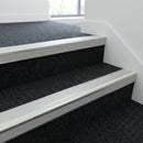 Ice grey insert aluminium stair nosing fitted to dark charcoal carpet treads in a modern office staircase