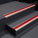 Red insert aluminium stair nosing fitted to dark grey vinyl steps in a cinema staircase