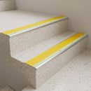 Yellow insert aluminium stair nosing fitted to pale terrazzo school staircase steps for high visual contrast