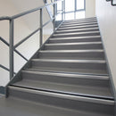 Anodised silver aluminium stair nosing with black rubber insert fitted over the front edge of every step on a commercial vinyl staircase