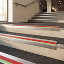 57x55mm rake back aluminium stair nosing with red PVC insert and green photoluminescent nose strip fitted on a commercial staircase