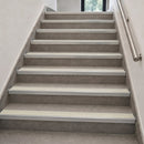 Aluminium rakeback stair nosings with canvas anti-slip inserts fitted to every step of a grey tiled internal staircase