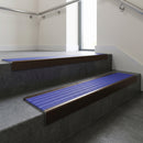Bronze square edge aluminium stair nosing with Mid Blue Castellated infill, fitted to a concrete step