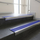 Polished Aluminium square edge aluminium stair nosing with Mid Blue Castellated infill, fitted to a concrete step