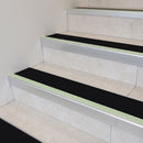 Black insert 63mm x 32mm aluminium stair nosing with photoluminescent front strip fitted to pale tiled steps