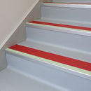 Red insert 63mm x 32mm aluminium stair nosing with photoluminescent front strip fitted to grey vinyl steps