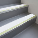 White insert 63mm x 32mm aluminium stair nosing with photoluminescent front strip fitted to grey vinyl steps