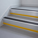 Black Anodised Aluminium insert in a 66x55mm square front aluminium stair nosing with 13mm Yellow riser highlight, fitted to interior steps