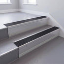 Black Castellated insert in a 66x55mm square front aluminium stair nosing with 13mm Polar Grey riser highlight, fitted to interior steps