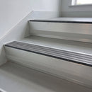 Granite Castellated insert in a 66x55mm square front aluminium stair nosing with 13mm Polar Grey riser highlight, fitted to interior steps