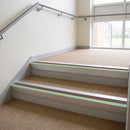 Aluminium stair nosing with brown PVC insert and green photoluminescent strip fitted on school stairs