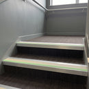 Square edge aluminium stair nosing with canvas PVC insert and green photoluminescent strip fitted on carpeted stairs