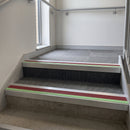 Square edge aluminium stair nosing with red PVC insert and green photoluminescent strip fitted on a commercial staircase
