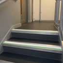Square edge aluminium stair nosing with white PVC insert and green photoluminescent strip fitted on dark stair treads