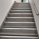 Aluminium stair nosings with black anti-slip PVC inserts fitted along every step of an internal tiled office stairwell