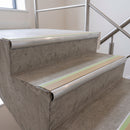 Beige insert 70x40mm bullnose aluminium stair nosing with photoluminescent strip fitted along two concrete steps in a commercial stairwell