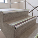 Brown insert 70x40mm bullnose aluminium stair nosing with photoluminescent strip fitted along two concrete steps in a commercial stairwell