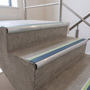 Cobalt Blue insert 70x40mm bullnose aluminium stair nosing with photoluminescent strip fitted along two concrete steps in a commercial stairwell
