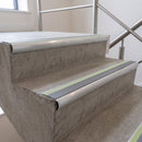 Dolphin Grey insert 70x40mm bullnose aluminium stair nosing with photoluminescent strip fitted along two concrete steps in a commercial stairwell