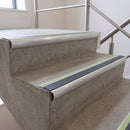 Midnight Grey insert 70x40mm bullnose aluminium stair nosing with photoluminescent strip fitted along two concrete steps in a commercial stairwell