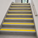 Aluminium stair nosings with high-visibility yellow anti-slip PVC inserts fitted to every step of an internal tiled commercial staircase