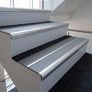 Bright polished aluminium bullnose stair nosing with twin mid grey inserts fitted to an office stairwell step