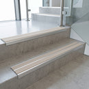 Beige double insert 91x32mm aluminium stair nosing fitted to concrete office steps in a glazed stairwell