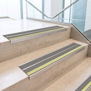Dolphin Grey double insert 91x32mm aluminium stair nosing fitted to concrete office steps with a green photoluminescent nose strip