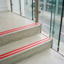 Red double insert 91x32mm aluminium stair nosing fitted to concrete office steps in a glazed stairwell