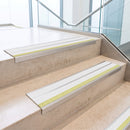 White double insert 91x32mm aluminium stair nosing fitted to concrete office steps with a green photoluminescent nose strip