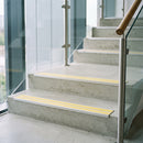 Yellow double insert 91x32mm aluminium stair nosing fitted to concrete office steps in a glazed stairwell