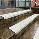 White Tredsafe 91x32mm aluminium stair nosing fitted to wet exterior entrance steps with a green photoluminescent nose strip