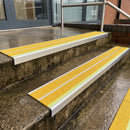 Yellow Tredsafe 91x32mm aluminium stair nosing fitted to wet exterior entrance steps with a green photoluminescent nose strip