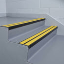 Satin black aluminium chevron stair nosing with twin yellow inserts fitted to two vinyl-covered public building steps