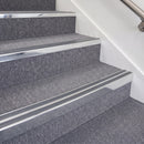 Bright polished double insert chevron stair nosing with dark grey inserts fitted on carpeted stairs