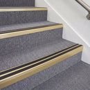Satin gold double insert chevron stair nosing with black inserts fitted on grey carpeted stairs