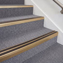Satin bronze double insert chevron stair nosing with brown inserts fitted on grey carpeted stairs