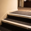 Bright polished aluminium stair nosing with White insert fitted to dark carpeted hotel lobby steps