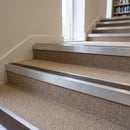 Mill finish aluminium stair nosing with Brown insert fitted to oatmeal carpet on a university library stair