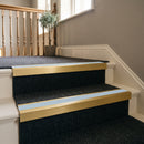 Satin gold aluminium stair nosing with Aura insert fitted to dark carpeted hotel landing stairs