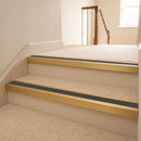 Satin gold aluminium stair nosing with Dark Grey insert fitted to cream carpet on a hotel corridor stair
