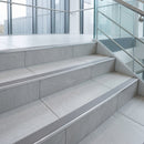 Wide 52mm aluminium tile-in stair nosing with G Grey RAL 7030 ribbed insert on pale grey porcelain office stairs