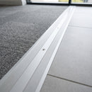 100mm matt silver aluminium cover plate screw fitted between carpet tile and porcelain tile in an office