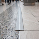 110mm aluminium cover plate screw fitted over an expansion joint between terrazzo and porcelain tile in a shopping centre walkway