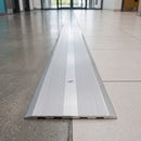 135mm matt silver aluminium cover plate screw fitted over a wide expansion joint in a leisure centre foyer