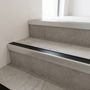 Slimline raked back 59x30mm aluminium stair nosing with a black anodised aluminium insert, on a satin aluminium bar, fitted directly to a bare concrete step