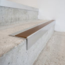 Slimline raked back 59x30mm aluminium stair nosing with a bronze anodised aluminium insert, on a satin aluminium bar, fitted directly to a bare concrete step