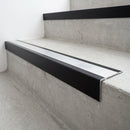 Slimline raked back 59x30mm aluminium stair nosing with a mill finish aluminium insert, on a black anodised bar, fitted directly to a bare concrete step