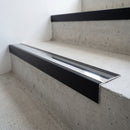 Slimline raked back 59x30mm aluminium stair nosing with a polished anodised aluminium insert, on a black anodised bar, fitted directly to a bare concrete step