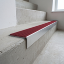 Slimline raked back 59x30mm aluminium stair nosing with a deep claret ribbed PVC insert, on a satin aluminium bar, fitted directly to a bare concrete step